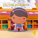 Detalhe frontal da caixa de atividades Doutora Brinquedos com recortes coloridos e acabamento artesanal