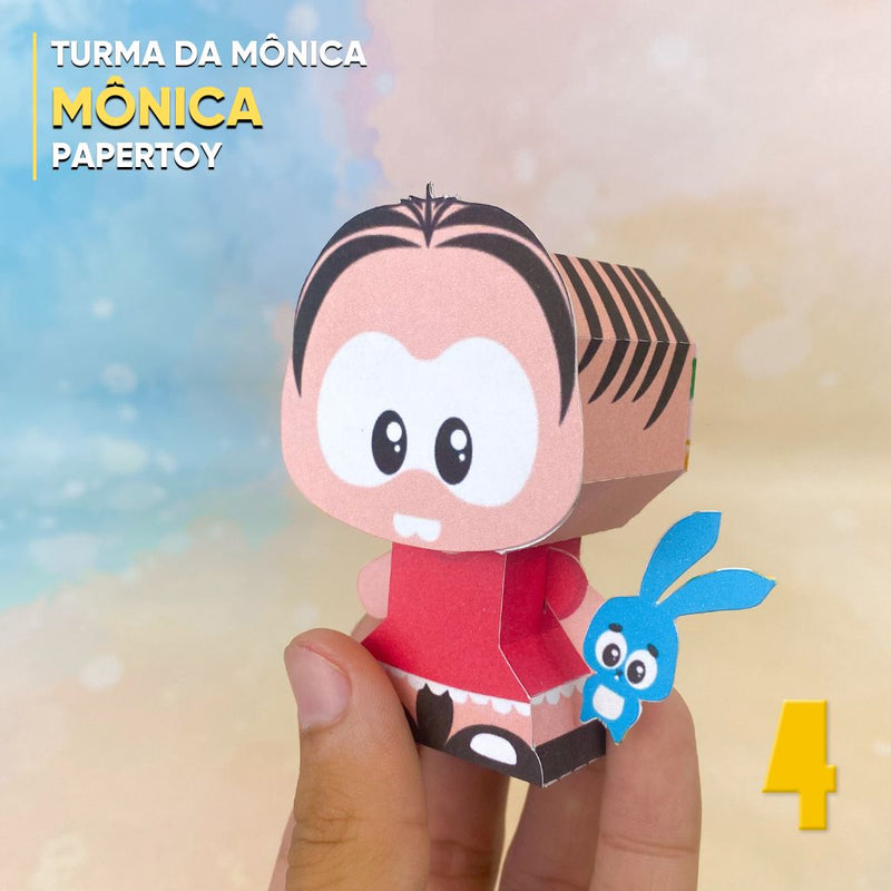 Vista lateral do Papertoy Mônica mostrando os detalhes do cabelo, sandálias e acabamento artesanal